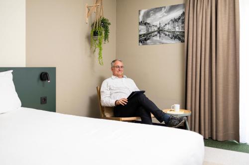 a man sitting in a chair in a room at Green Park Hotel Brugge in Bruges
