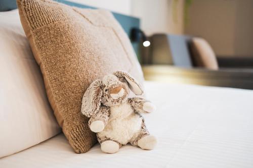 a stuffed animal sitting on a bed next to a pillow at Green Park Hotel Brugge in Bruges