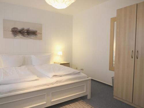 um quarto branco com uma cama branca e um candeeiro em Fernsicht-12b-EG em Wenningstedt
