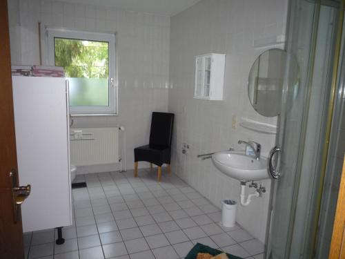 a bathroom with a sink and a black chair at Ferienwohnung Alte Kämpe in Heede