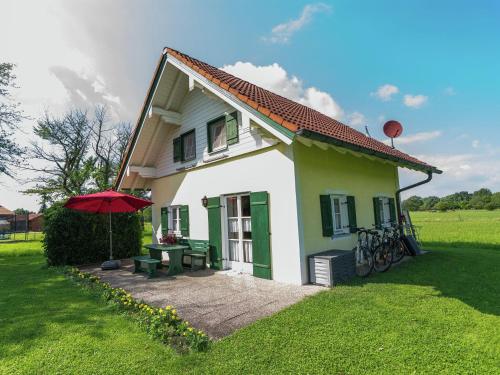 a small house with a picnic table and an umbrella at Alluring Holiday Home in Ubersee with Whirlpool in Übersee