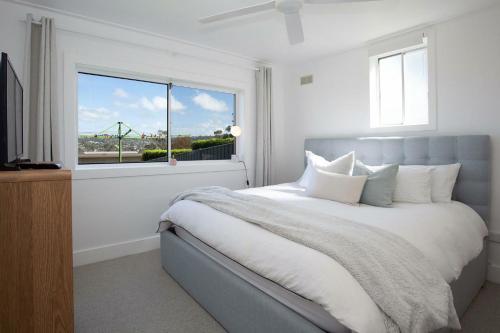 um quarto com uma cama grande e uma janela em Palm Springs in Collaroy em Collaroy