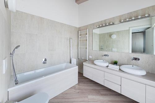 uma casa de banho com 2 lavatórios, uma banheira e um espelho. em Residenza Miralago Penthouse by Wonderful Italy em Desenzano del Garda