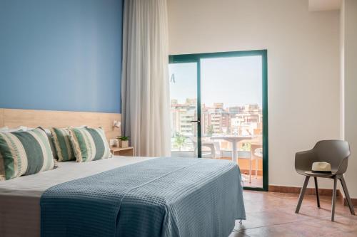 a bedroom with a bed and a chair and a balcony at ALEGRIA Colonial Mar Aquafun in Roquetas de Mar