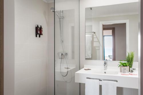a white bathroom with a shower and a sink at ALEGRIA Colonial Mar Aquafun in Roquetas de Mar