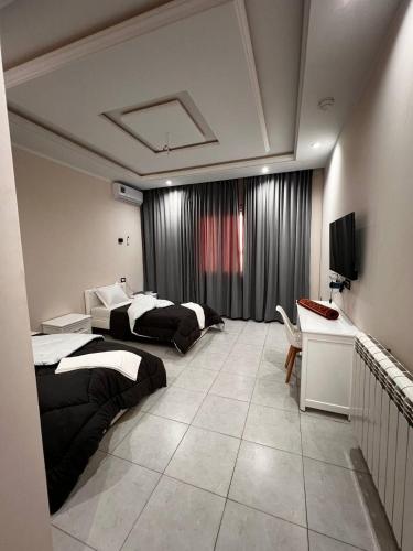 1 dormitorio con 2 camas y TV. en Hotel Eloued فندق الوادي, en Tiksebt