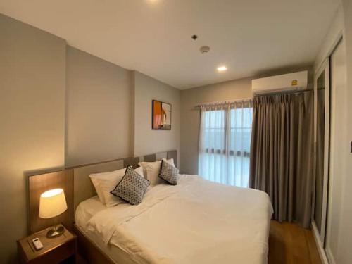 a bedroom with a large white bed with a window at Modern style room with sky pool 古城边天际泳池公寓 in Chiang Mai
