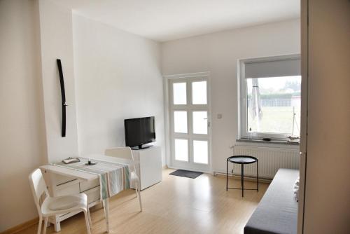 a white living room with a desk and a tv at Haus JuliaN Wohnung 1 in Ueckermünde
