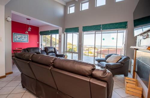a living room with a brown leather couch and chairs at Pikkewyn Unit 1 in Agulhas