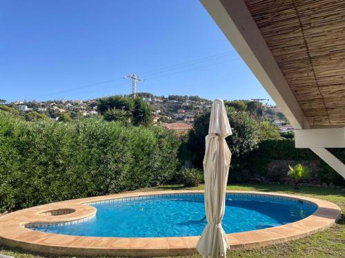 een witte parasol en een zwembad met een parasol bij Nice holiday house with pool at La Sella Golf between Denia and Javea in Pedreguer