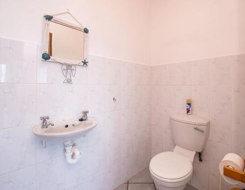 a white bathroom with a toilet and a sink at Pikkewyn Unit 1 in Agulhas