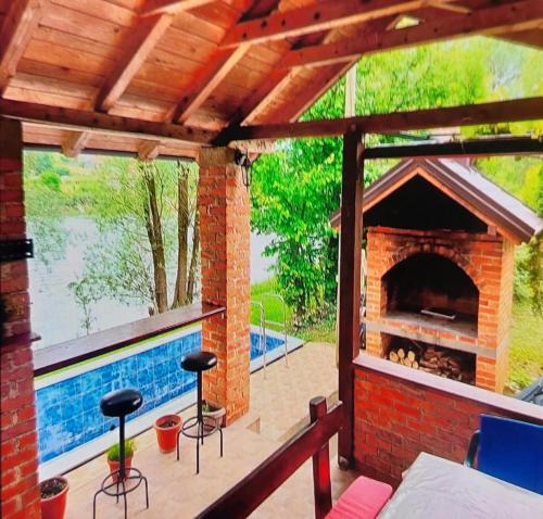 a patio with a brick fireplace and a swimming pool at Vikendica Raj u prirodi in Prijedor