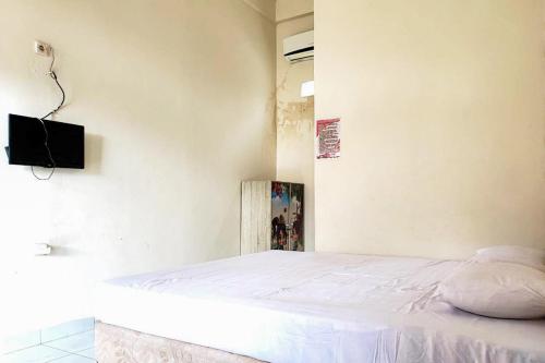 a bedroom with a bed and a tv on the wall at Dhamar Prabujaya Redpartner in Prabumulih