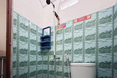 a bathroom with green tiled walls and a toilet at Dhamar Prabujaya Redpartner in Prabumulih
