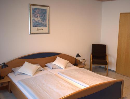 1 dormitorio con 1 cama con silla y una foto en la pared en Ferienwohnung Reis, en Sankt Aldegund