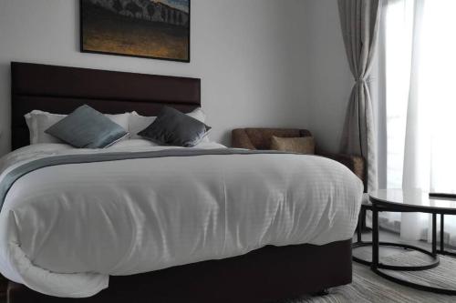 a bedroom with a large white bed and a table at Epitome Apartment, Swara Ranch-Nanyuki in Nanyuki
