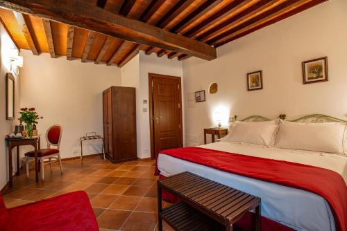 a bedroom with a bed and a table and a chair at Torciano Hotel Vecchio Asilo in San Gimignano