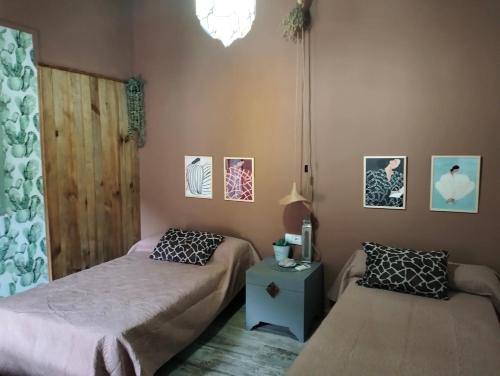 1 dormitorio con 2 camas, mesa y fotografías en Casa rural La Libelula Ayna, en Ayna