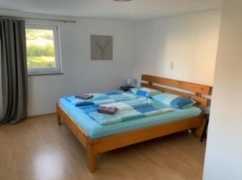 1 dormitorio con cama con sábanas azules y ventana en Fewo Max, en Münchweier