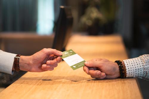 two people holding a credit card in their hands at Green Park Hotel Brugge in Bruges