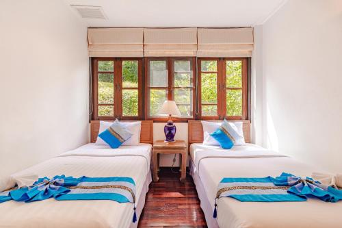 two beds in a room with two windows at Kamala Beach Estate Resort - SHA Extra Plus in Kamala Beach