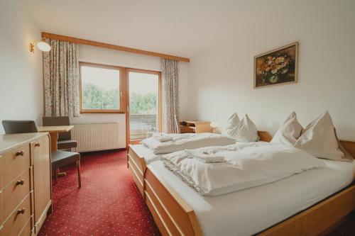 a bedroom with two beds and a desk and a window at Hotel Semriacherhof in Semriach