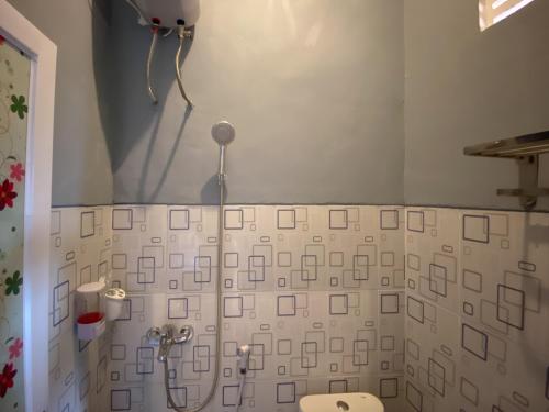 a bathroom with a shower with white tiles and a toilet at Duta Elite Kostel Syariah near RSUD Caruban Redpartner in Madiun