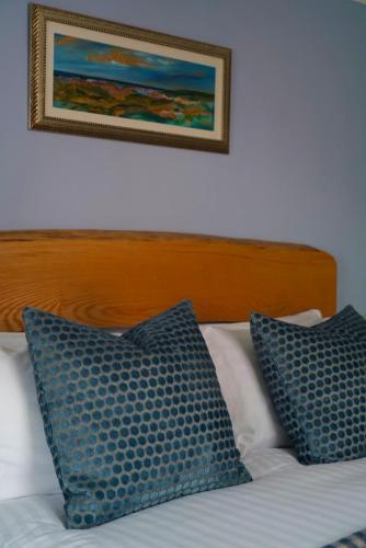 a bed with two blue pillows and a picture on the wall at Arosfa Harbourside Aberaeron in Aberaeron