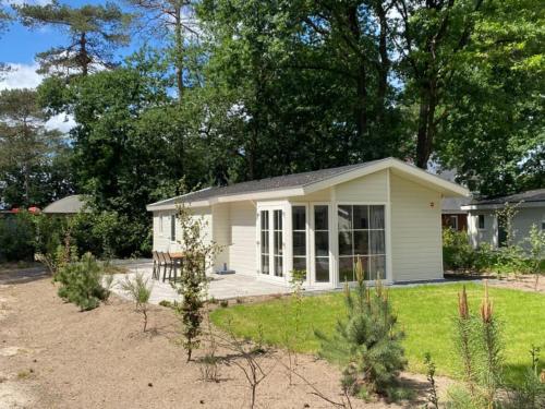 a small white house with a patio in a yard at Luxe Chalet Inn Otterlo op de Veluwe aan het Water! in Otterlo
