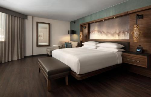 シータックにあるシアトル エアポート マリオットの白い大型ベッドと椅子が備わるホテルルームです。