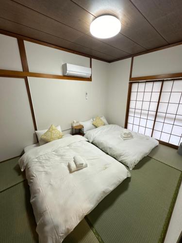 two beds in a room with two windows at 桜Home in Tokyo