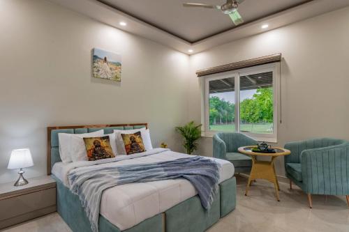 a bedroom with a bed and two chairs and a window at Elivaas Enchantia Luxury 6BHK Villa with Pvt Pool in Gurgaon in Bhundsi