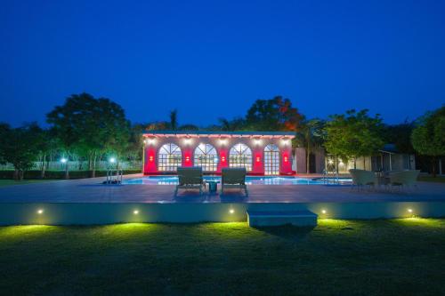 a lit up building with red lights at night at ELIVAAS 6 BHK Farmhouse with Pvt Pool & Garden - Enchantia in Bhundsi