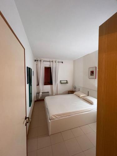 a white bedroom with a bed and a window at Residenze Coda Cavallo in San Teodoro