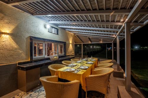 a dining room with a long table and chairs at ELIVAAS 6 BHK Farmhouse with Pvt Pool & Garden - Enchantia in Bhundsi