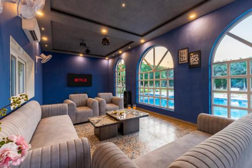 a living room with blue walls and couches at Elivaas Enchantia Luxury 6BHK Villa with Pvt Pool in Gurgaon in Bhundsi