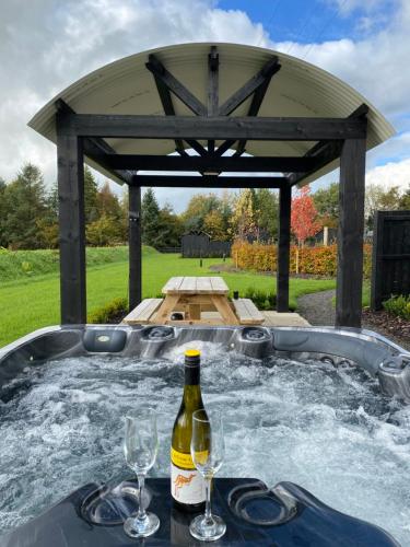 a hot tub with a bottle of wine and glasses at Shepherds Huts at Ballyness Farm in Dungiven