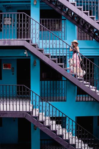 a woman sitting on the stairs of a blue building at The Quba Boutique Hotel Pattaya in Pattaya Central
