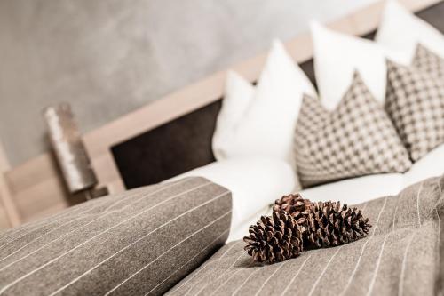 a bed with pillows and two pine cones on it at Josef Mountain Resort in Avelengo