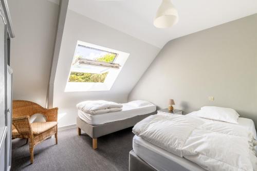 a attic bedroom with two beds and a chair at Bel appartement à 300m des plages in Carnac