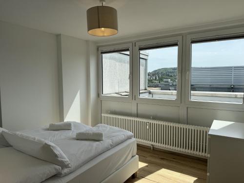 een witte slaapkamer met een bed en 2 ramen bij Penthouse in zentraler Lage in Pforzheim