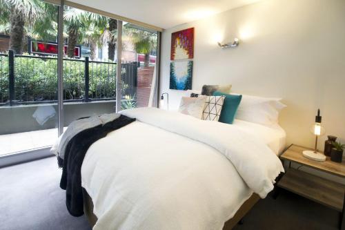 a bedroom with a white bed and a large window at Urban Sea Drift in Melbourne