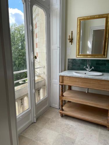 ein Bad mit einem Waschbecken, einem Spiegel und einem Fenster in der Unterkunft Château De L'aubrière - Teritoria in Tours