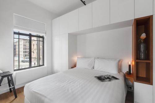 een witte slaapkamer met een bed met een tijdschrift erop bij Spring on Collins An elegant Suite on Collins Street in Melbourne