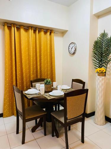 a dining room with a table and chairs and a clock at Hello condo in Manila