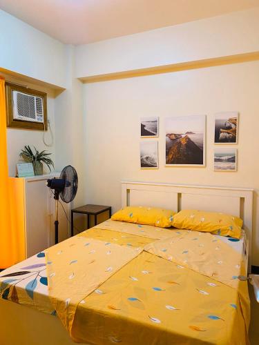 um quarto com uma cama com um edredão amarelo em Hello condo em Manilla