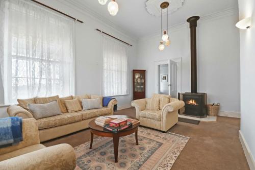 a living room with a couch and a table and a fireplace at Mollison Park Farm in Emu Flat
