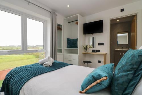 a bedroom with a bed with two blue pillows at Valley View in Helston