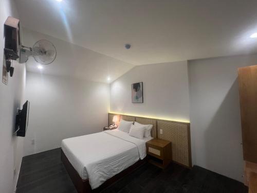 a hotel room with a white bed and a tv at A25 Hotel - 14 Hồ Huấn Nghiệp in Ho Chi Minh City