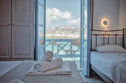 a hotel room with towels on a bed with a balcony at Hotel Mantalena in Antiparos